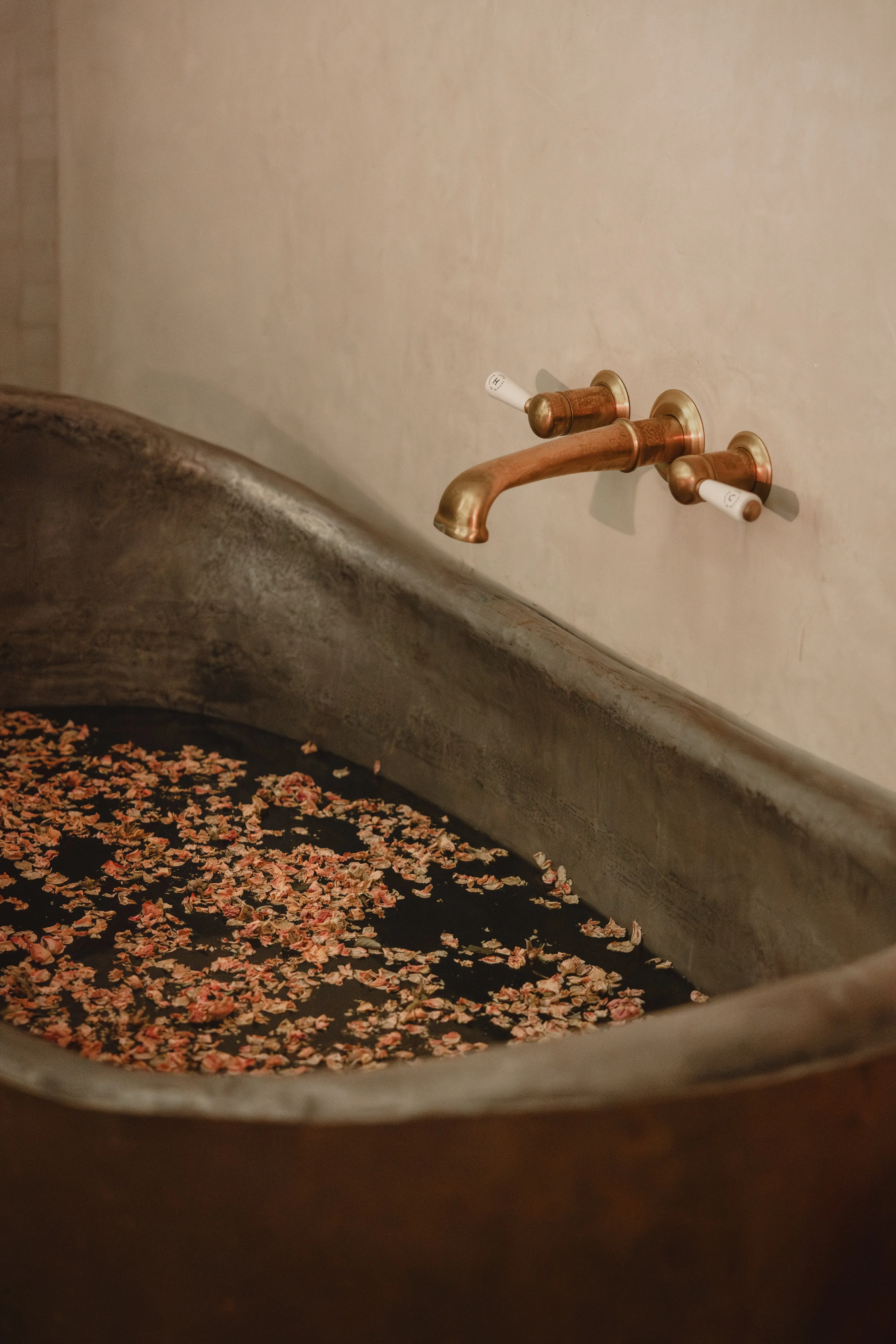 A copper bathtub with rose petals